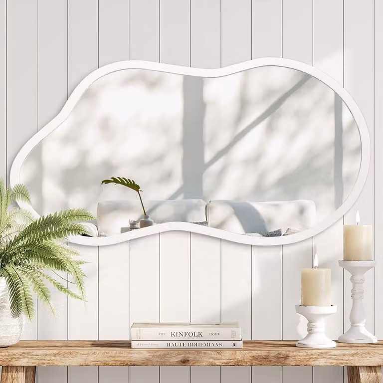 Decoratieve kleine wandspiegel met onregelmatige houten tafel in het wit voor de slaapkamer, kleedkamer of badkamer